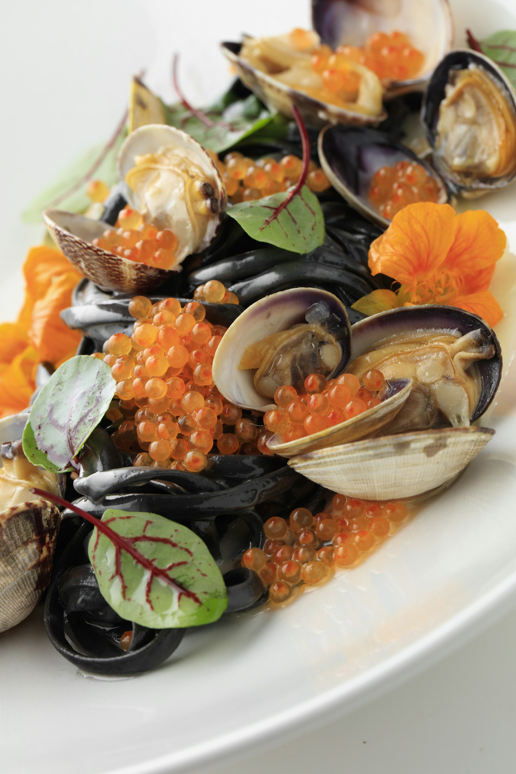Gourmet seafood pasta with clams and roe garnish.