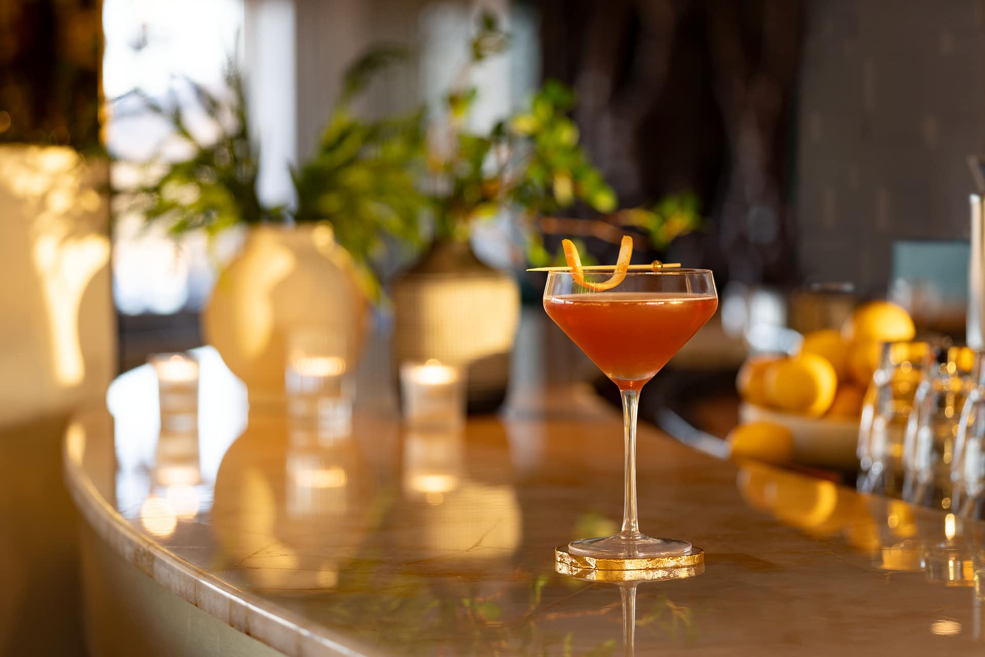 Signature cocktail on a sunlit marble bar.