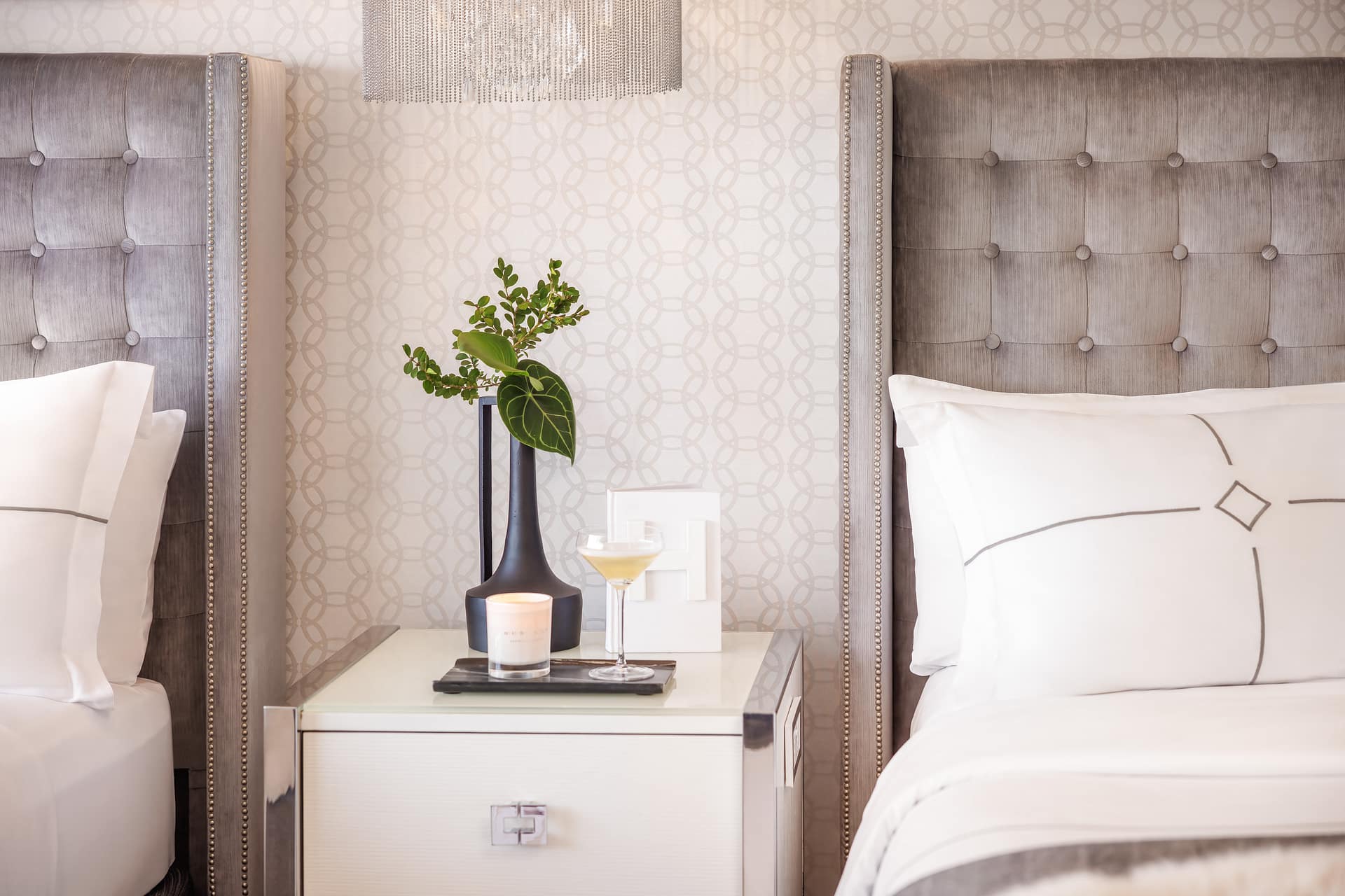 Cozy hotel room nightstand with drink and candle.