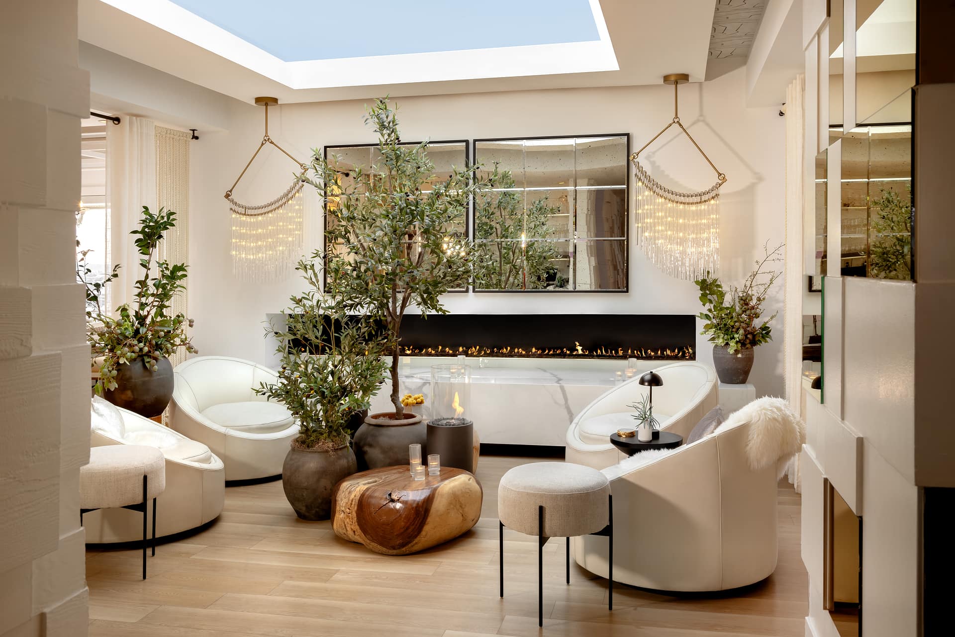 Elegant lounge with fireplace, greenery, and modern lighting.