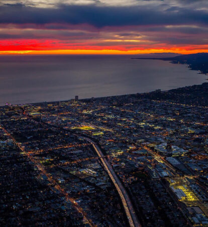 Aerial coastal city at sunset with glowing horizon