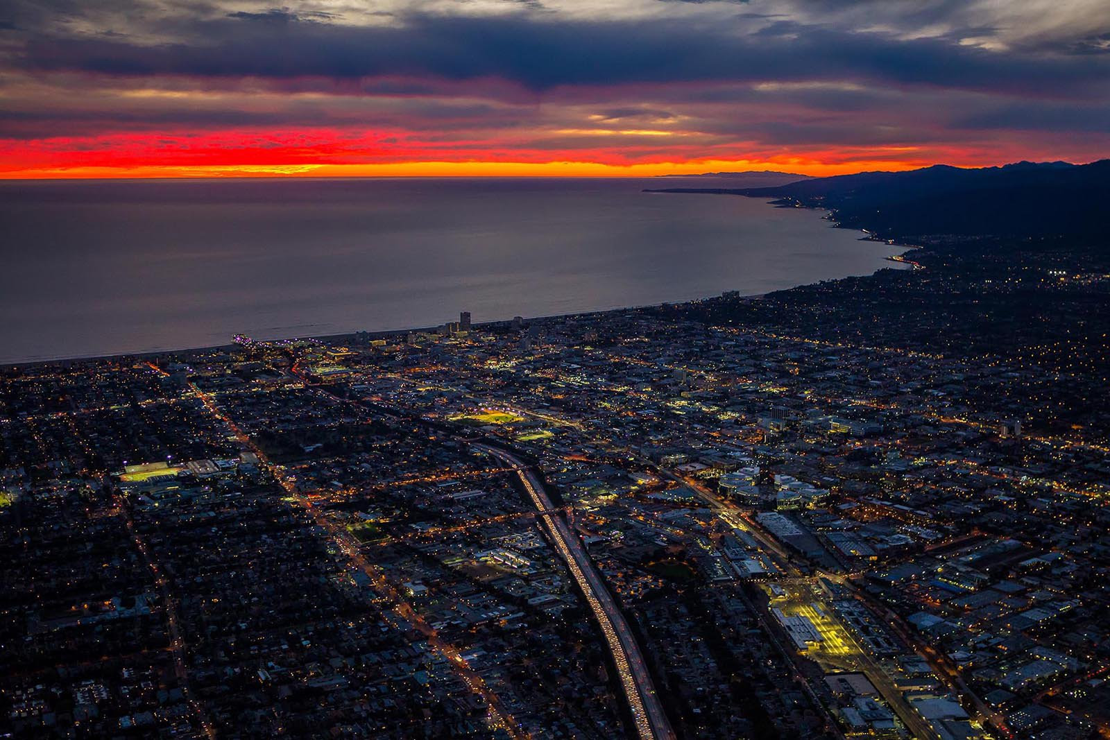Aerial coastal city at sunset with glowing horizon