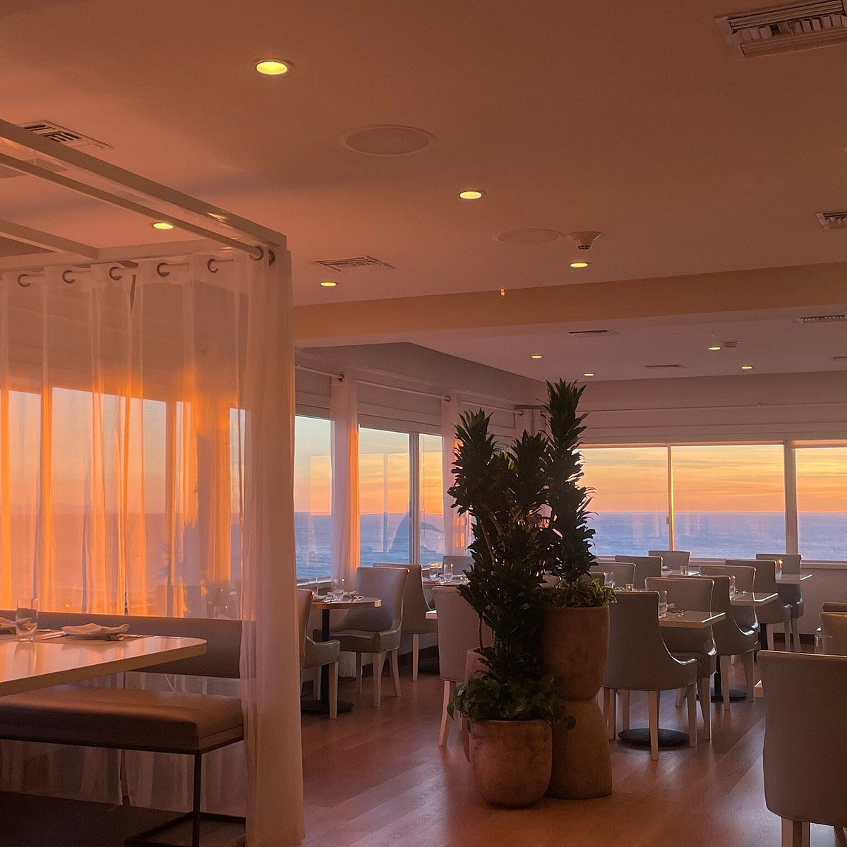 Modern restaurant interior with sunset light and ocean views