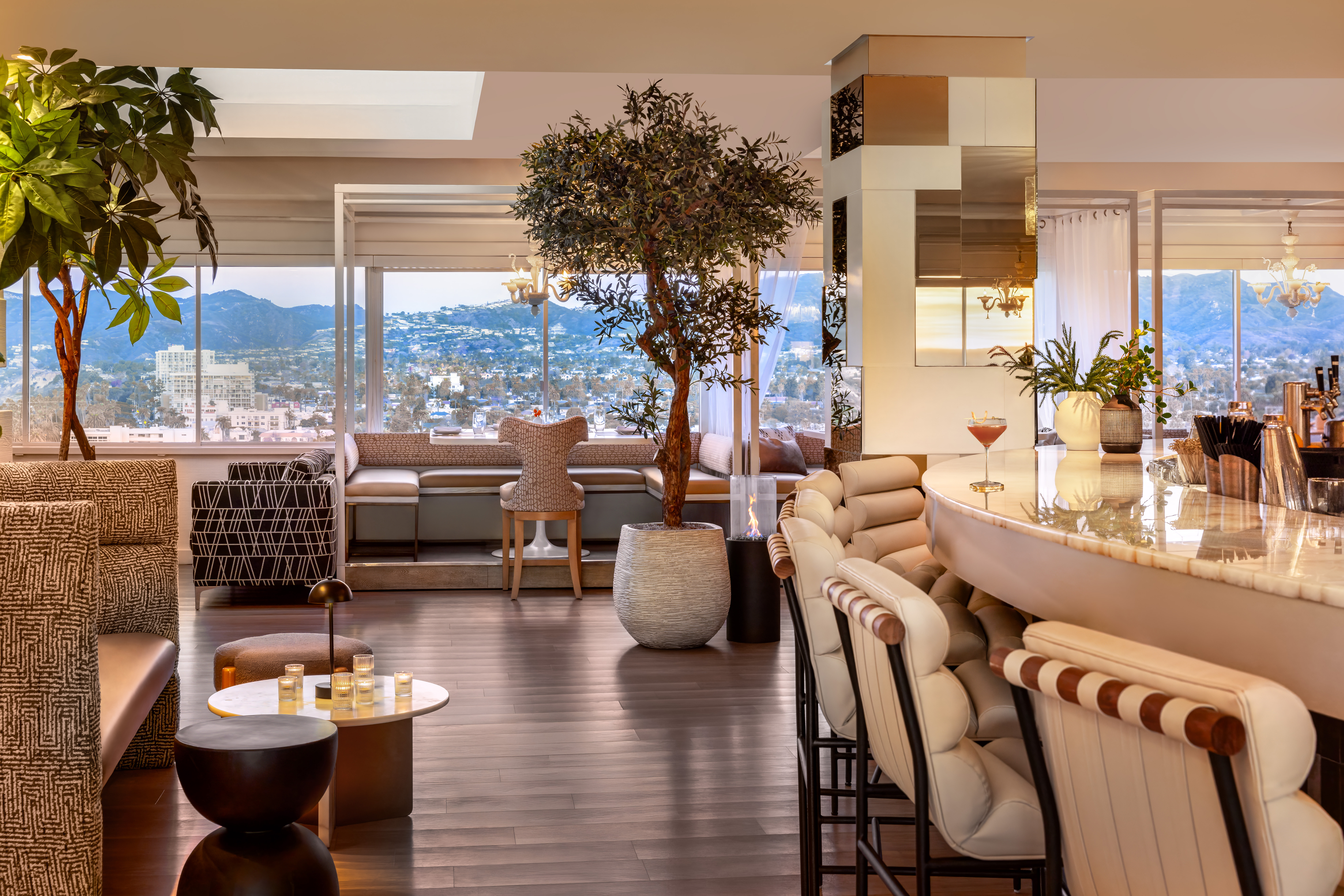Stylish lounge with bar seating, plants, and large windows overlooking a cityscape